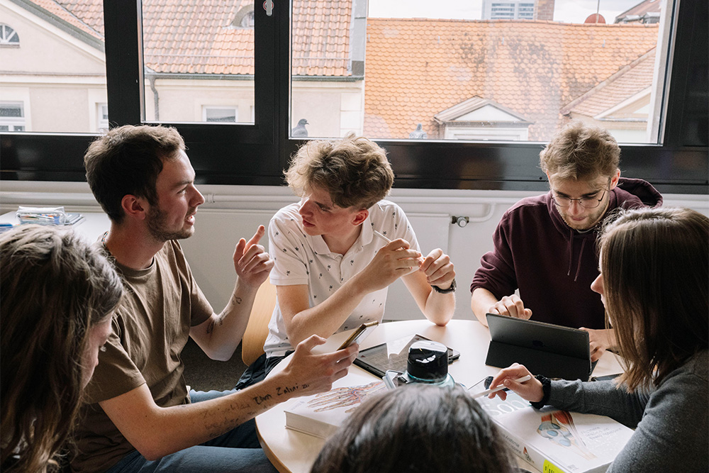 Mehre junge Menschen sitzen zusammen in einem Besprechungsraum und unterhalten sich.