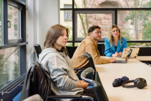 Junge Menschen sitzen in einem Klassenraum und hören jemandem zu.