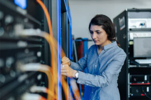 Eine Frau steht vor einem Server und stellt etwas ein.